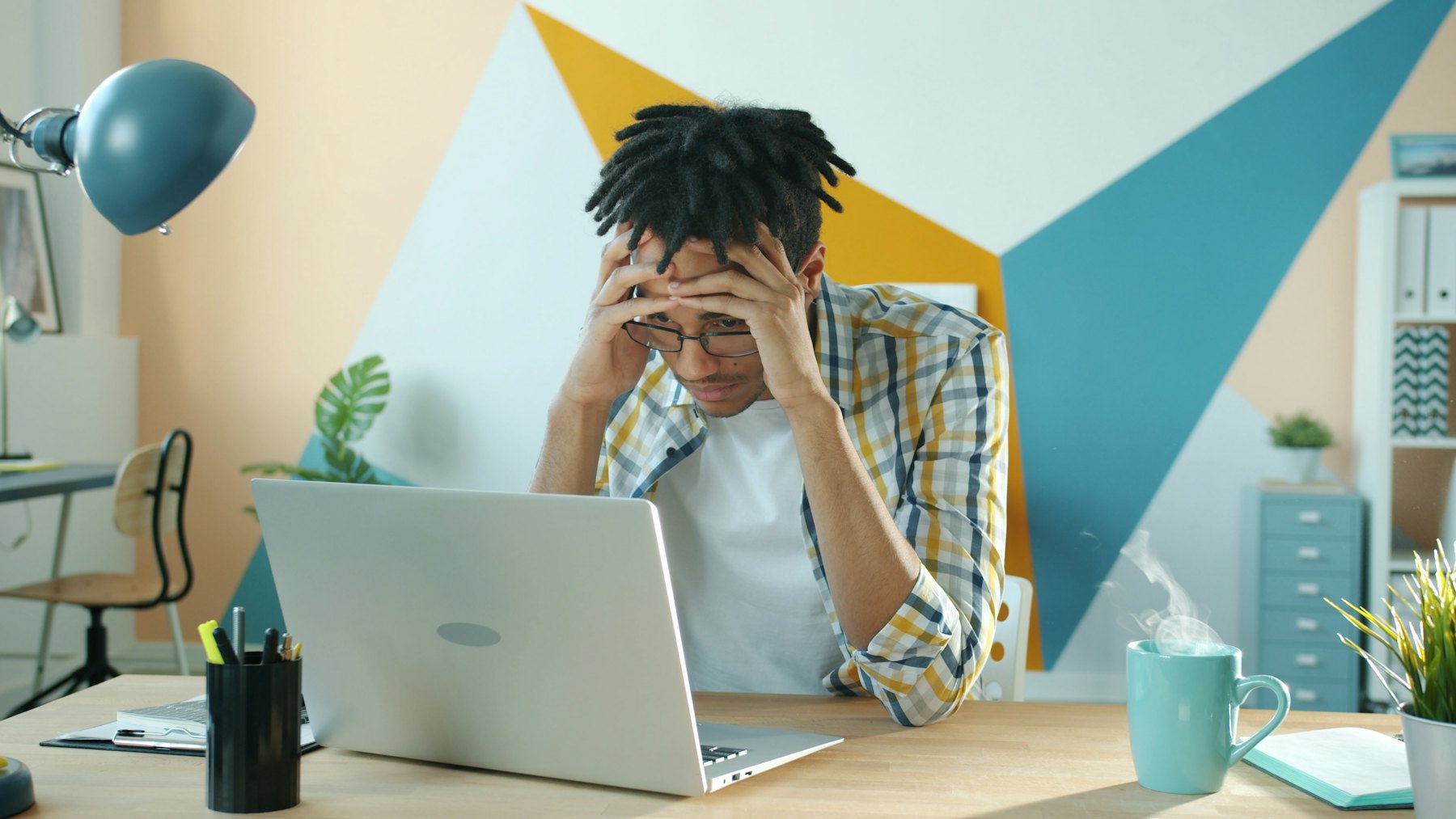 A founder at his desk holding his head, surrounded by unfinished work